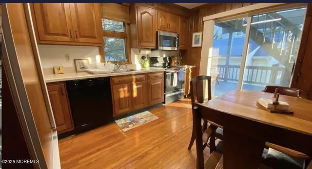 a kitchen with kitchen island granite countertop a sink cabinets and wooden floor