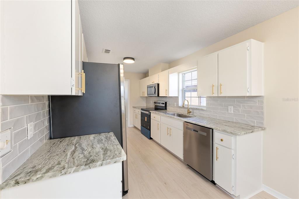 17549 Southeast 115th Terrace Road Summerfield, FL 34491 - Photo 13 of 56 a kitchen with granite countertop a sink stove and refrigerator