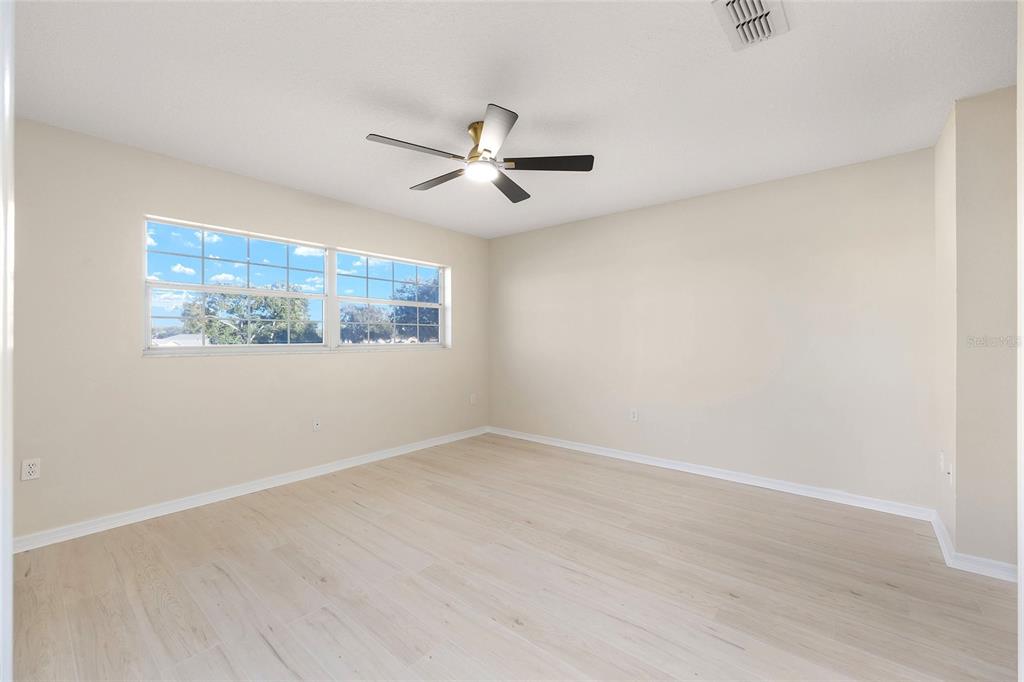 17549 Southeast 115th Terrace Road Summerfield, FL 34491 - Photo 25 of 56 an empty room with wooden floor ceiling fan and windows