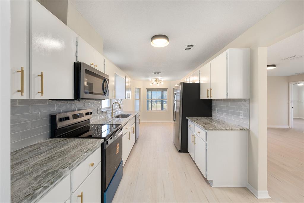17549 Southeast 115th Terrace Road Summerfield, FL 34491 - Photo 7 of 56 a kitchen with stainless steel appliances granite countertop a sink stove and refrigerator
