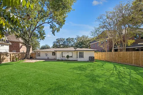 a view of a house with a big yard and large trees
