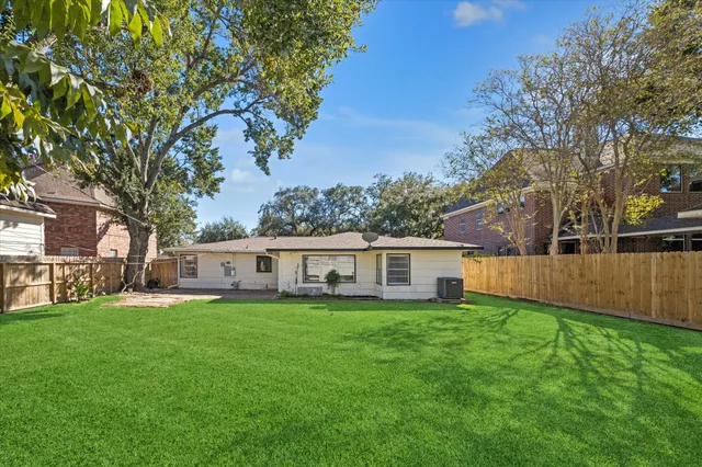 a view of a house with a big yard and large trees