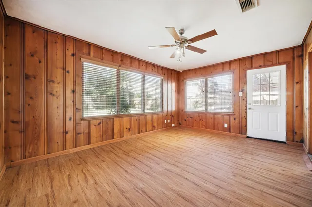 a view of an empty room with a window and wooden floor