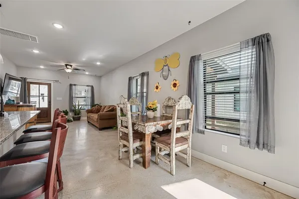 a kitchen with stainless steel appliances kitchen island granite countertop a refrigerator and a dining table