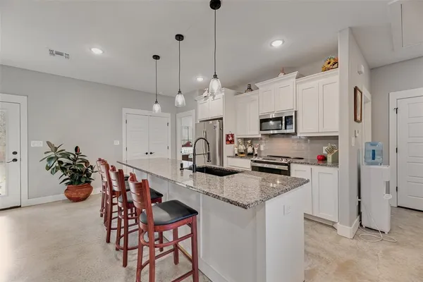 a kitchen with stainless steel appliances a refrigerator a stove a sink a dining table and chairs