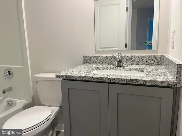 a bathroom with a granite countertop toilet sink and mirror