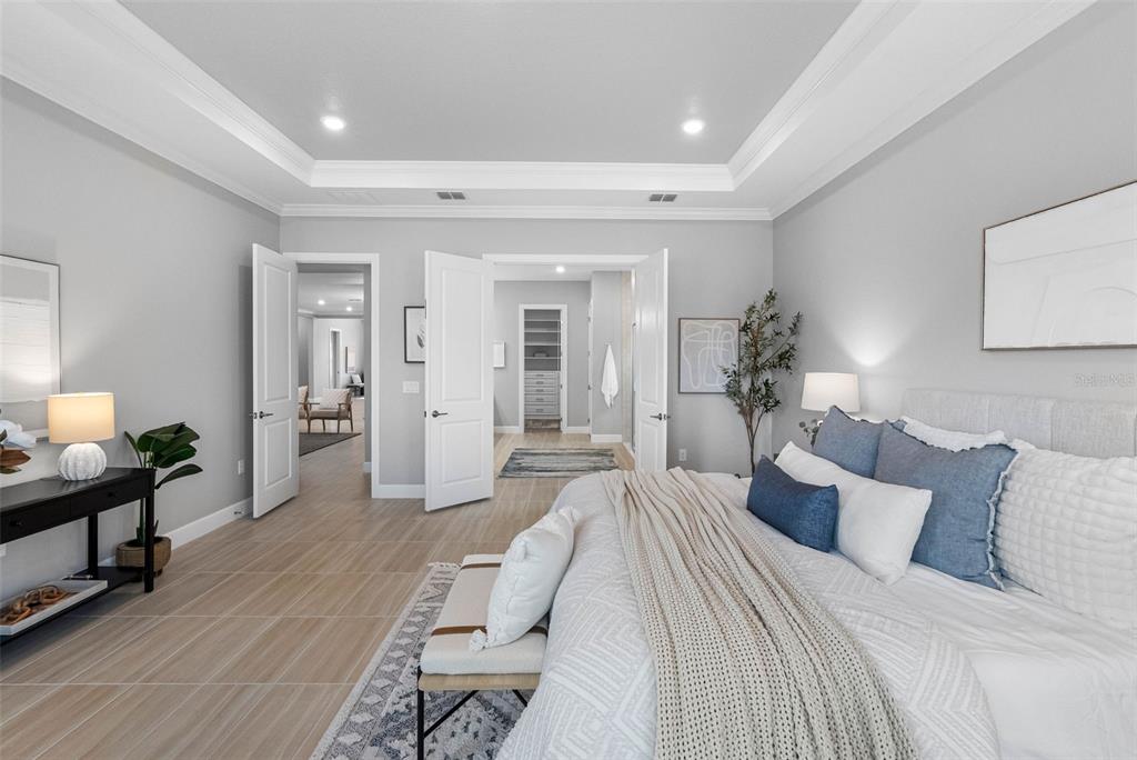 4795 Freccia Loop Wesley Chapel, FL 33543 - Photo 22 of 51 a spacious bedroom with a bed and a chandelier