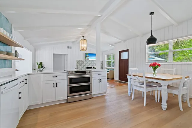 a kitchen with stainless steel appliances a dining table chairs stove and white cabinets