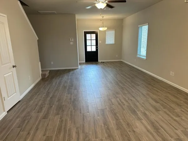 an empty room with wooden floor and windows