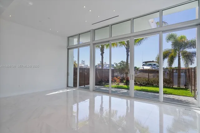 a view of an empty room with floor to ceiling window and palm tree