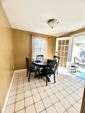 a living room with a table chairs and a dining table with wooden floor