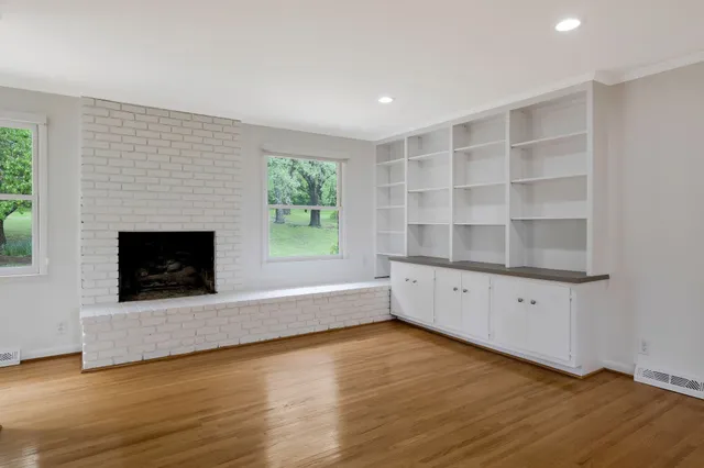 a view of an empty room with a window and fireplace