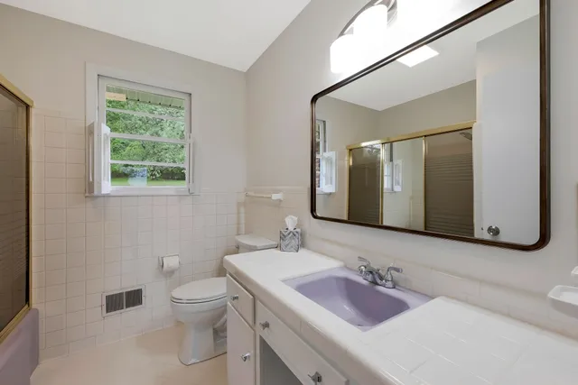 a bathroom with a granite countertop sink toilet and mirror