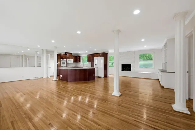 a view of an empty room with kitchen and a window