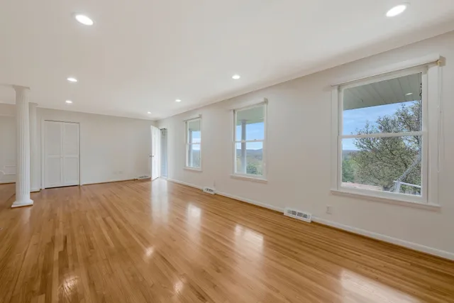 a view of an empty room with wooden floor and a window