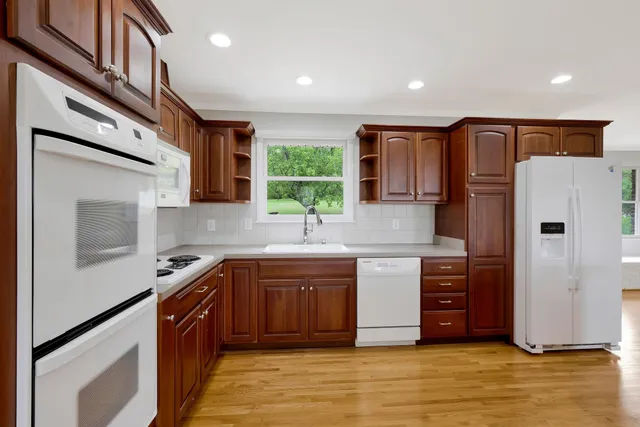 a kitchen with stainless steel appliances granite countertop a refrigerator a sink dishwasher a stove with wooden cabinets and floor