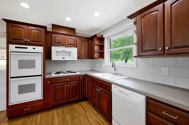 a kitchen with stainless steel appliances granite countertop wooden cabinets and a stove top oven