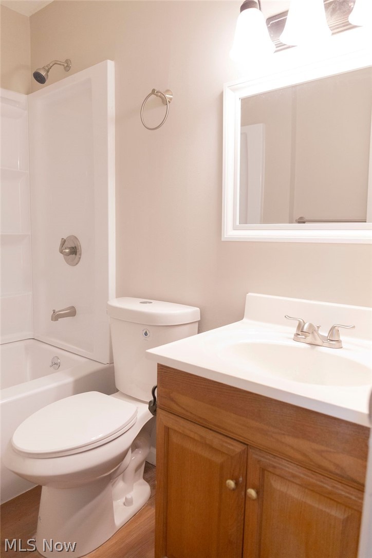 3644 Padanarum Road Geneva, OH 44041 - Photo 14 of 19 Bathroom featuring a wood-finish vanity with a white countertop and integrated sink, a white toilet, and a white tub/shower combination with a brushed nickel showerhead and faucet