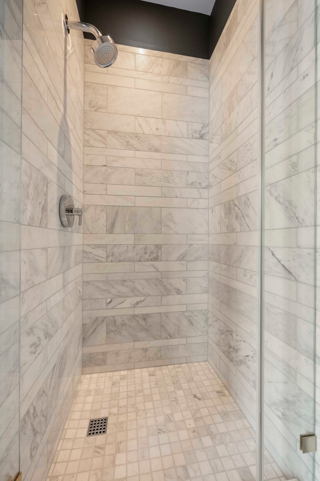 210 Lavaca Street, Unit 2706 Austin, TX 78701 - Photo 28 of 32 Shower enclosure featuring floor-to-ceiling rectangular tile, square tile flooring, a chrome shower head, a chrome control handle, and a frameless glass panel