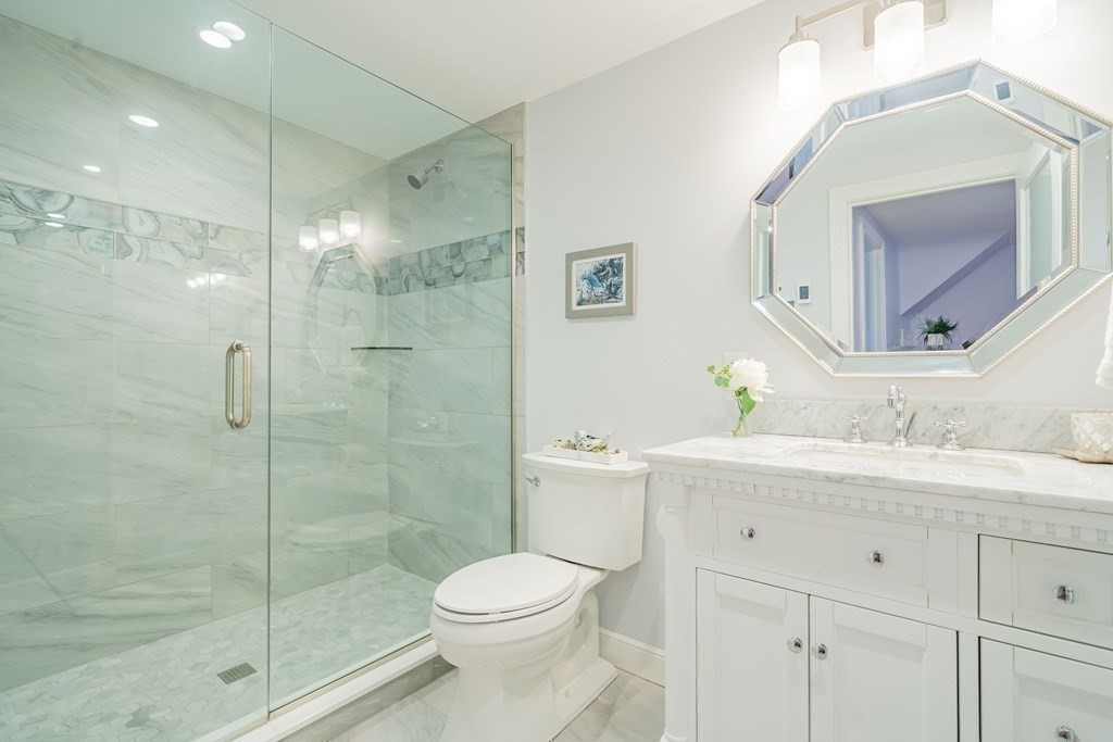 51 Robinson Road Lexington, MA 02420 - Photo 29 of 42 a bathroom with a toilet a sink a glass door a shower a mirror a vanity and window