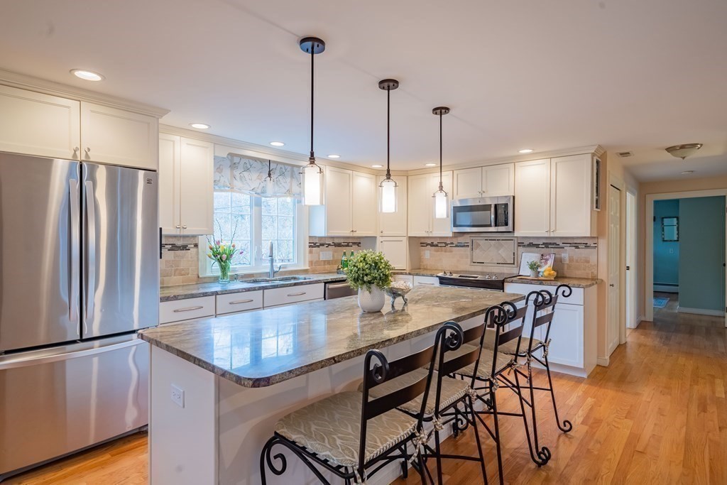 51 Robinson Road Lexington, MA 02420 - Photo 10 of 42 a kitchen with stainless steel appliances granite countertop a stove a refrigerator a kitchen island a dining table and chairs with wooden floor