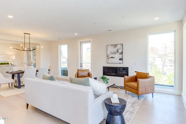 a living room with furniture kitchen view and a wooden floor