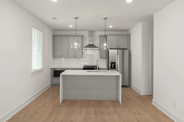 a large kitchen with stainless steel appliances a large counter top a sink a refrigerator and a window