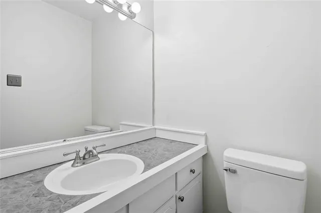 a bathroom with a granite countertop sink a toilet and a mirror