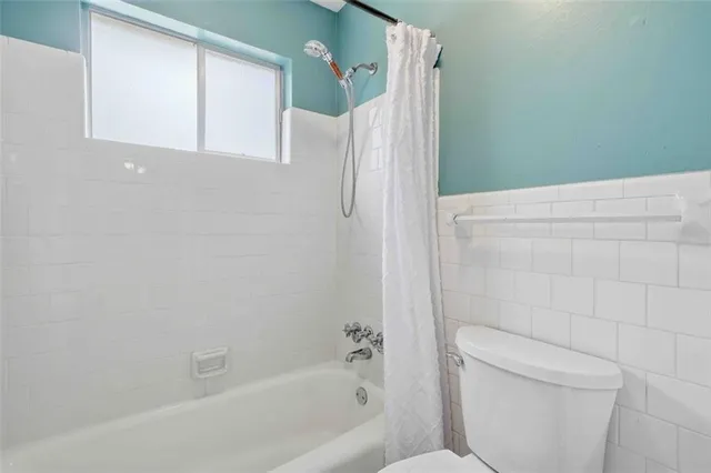 a bathroom with a shower a toilet and a window