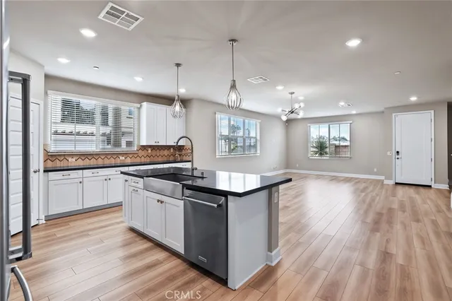 a kitchen with stainless steel appliances granite countertop hardwood floor sink stove and wooden cabinets