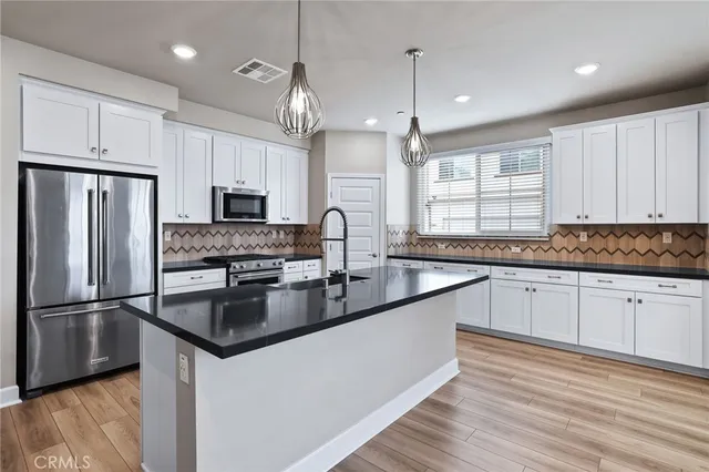 a kitchen with stainless steel appliances granite countertop a sink refrigerator and microwave