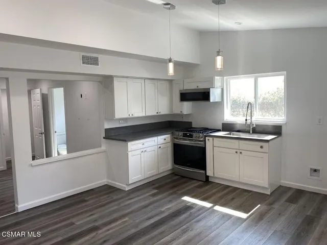 a kitchen with granite countertop a stove a sink and a microwave