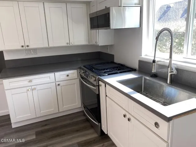 a kitchen with white cabinets and sink