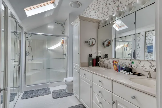 a bathroom with a granite countertop sink toilet and shower glass cabinet