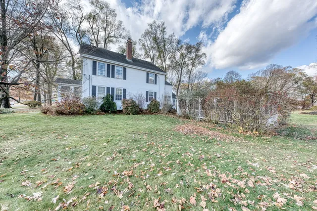 a view of a field with a white house in the background