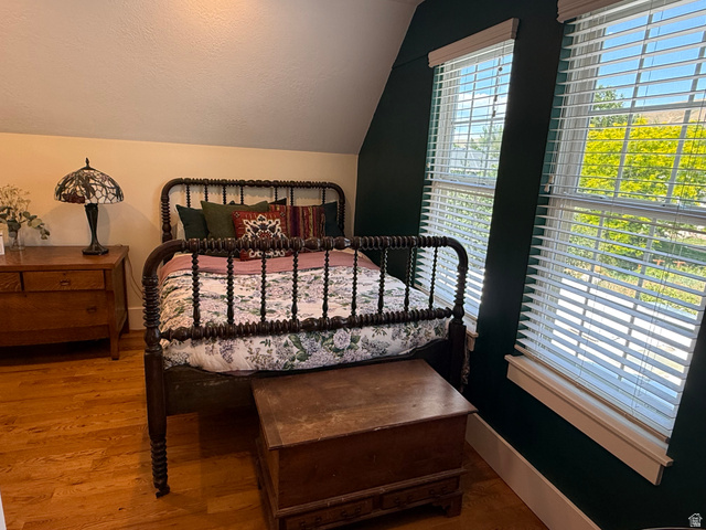 776 Canyon Road Hyde Park, UT 84318 - Photo 22 of 57 Bright bedroom featuring two windows with horizontal blinds, hardwood flooring, and a unique architectural ceiling line