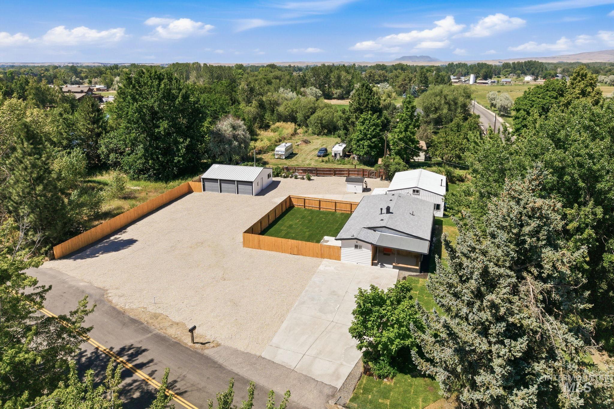 2152 Artesian Road Eagle, ID 83616 - Photo 43 of 50 Expansive gravel lot featuring a three-bay detached garage, wood privacy fencing, and a manicured lawn