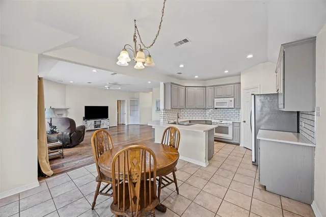 a kitchen with stainless steel appliances granite countertop a sink a stove a refrigerator cabinets and a dining table