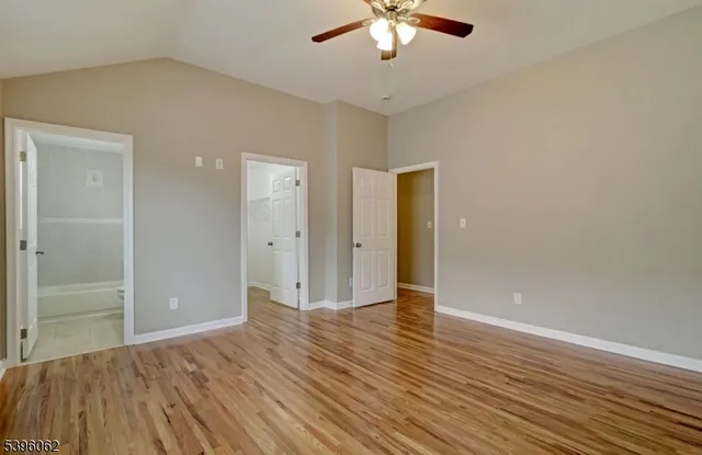 an empty room with wooden floor and a ceiling fan
