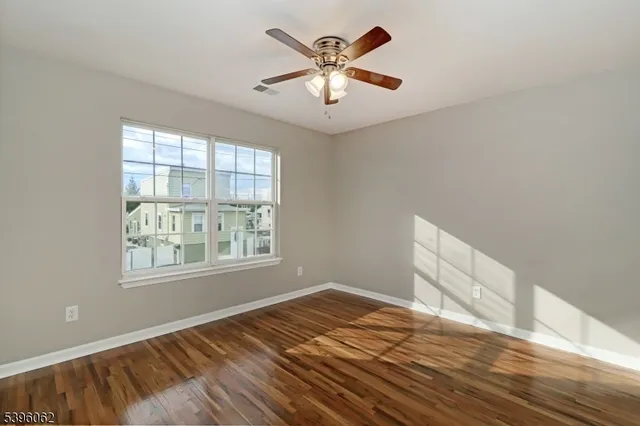 a view of an empty room with window and wooden floor