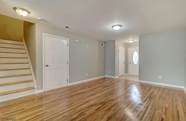 a view of an empty room with wooden floor and stairs