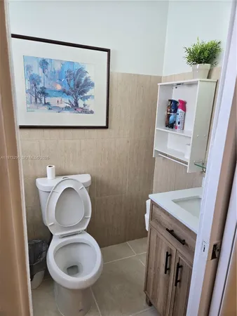 a bathroom with a toilet a sink and wooden floor