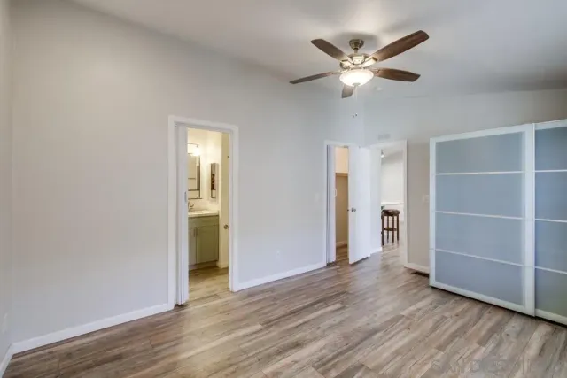 an empty room with wooden floor and ceiling fan
