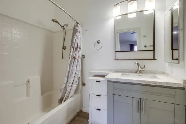 a bathroom with a granite countertop sink a mirror and shower