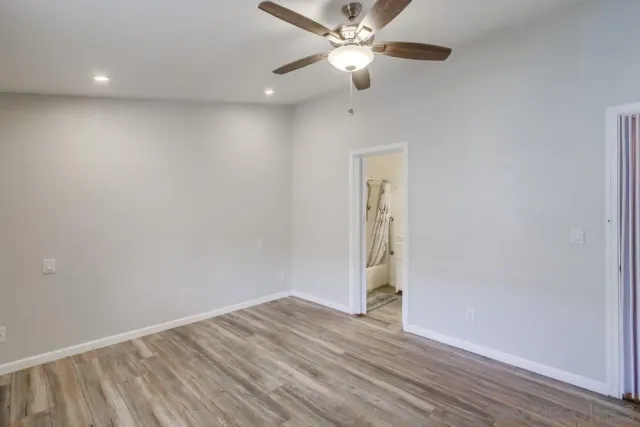 an empty room with wooden floor ceiling fan and window