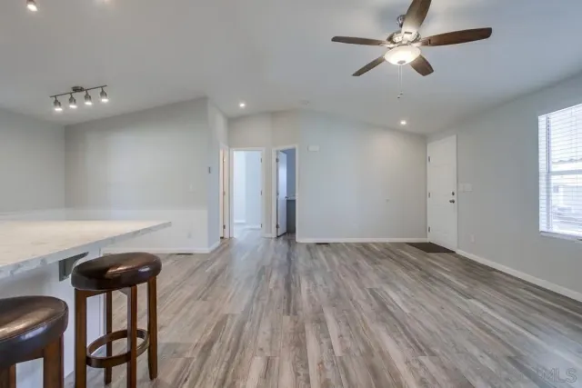 a view of empty room with wooden floor and fan
