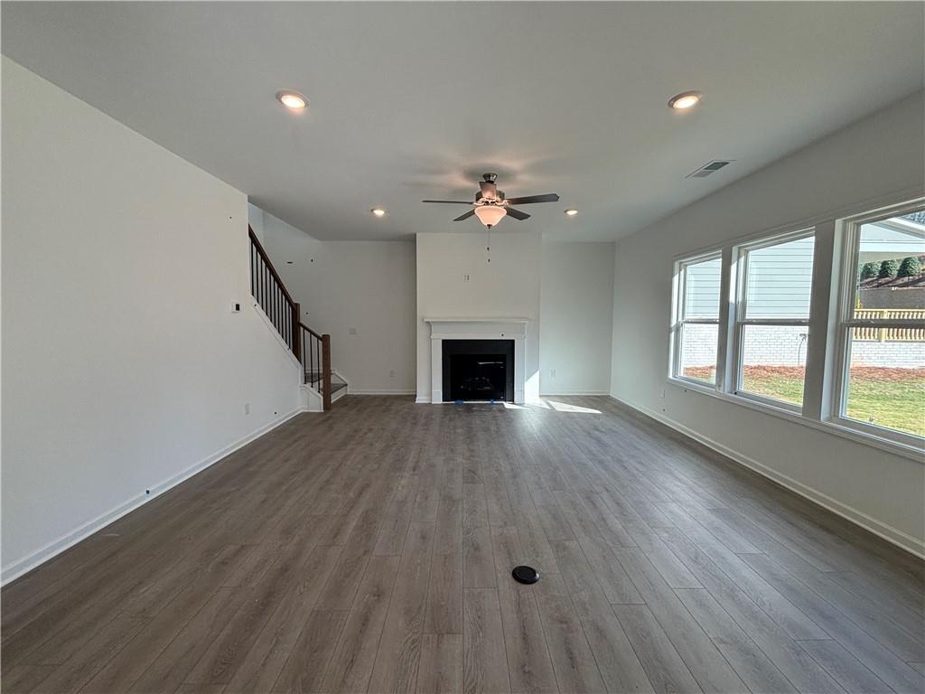 6125 Kismet Road Buford, GA 30518 - Photo 13 of 40 an empty room with wooden floor fireplace and windows