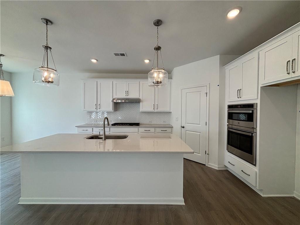 6125 Kismet Road Buford, GA 30518 - Photo 9 of 40 a large kitchen with kitchen island a stove a sink a refrigerator and white cabinets