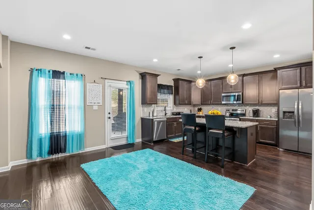 a kitchen with stainless steel appliances granite countertop a sink a stove a refrigerator cabinets and chairs