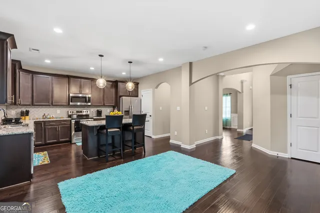 a kitchen with stainless steel appliances granite countertop a stove top oven a dining table and chairs with wooden floor